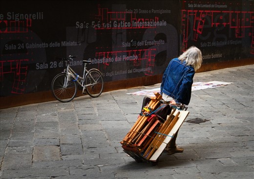 Uffizi Artist: Outside the Uffizi Gallery artists set up their easels and sell their (or someones's) art work.  It seems reamarkable that tourists would come out of the Uffizi which holds one of the best collections of art in the world and buy a painting from a street vendor.  This one got tired of waiting for a sale and packed up for home