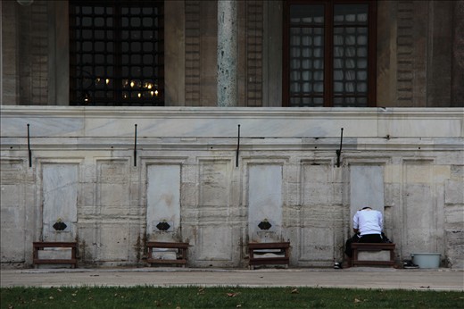 This boy was lost in thought as he  was washing his feet before prayer. 