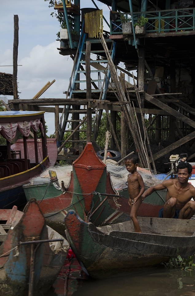 A father and son undock their boat from their house in Kompong Phluk. Cambodia.
