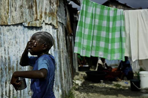 A boy washes himself on the street. It was his only shower all week.