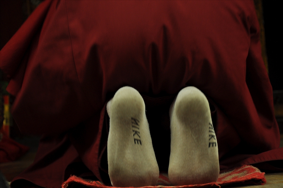A monk in the western Qing Hai prays in worn Nike socks.