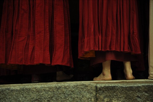 A monk's bare feet show from underneath his robes.