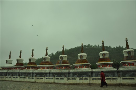 A monk walks by a monastery's mountain-side pillars in Qing Hai.