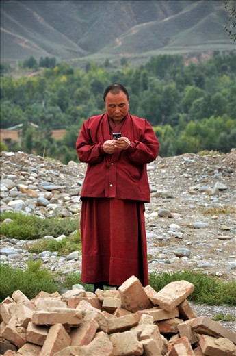 A monk texts on his cell phone on the grounds of a monastery.