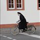 Nun on the run....A nun takes off pedaling after a stop light turns green.: by stacysimmering, Views[281]