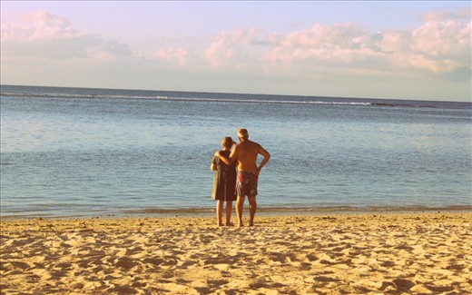 Elderly loving couple on beach at Flic en Flac, Mauritius, staring into the horizon, showing that the possibility of soulmates exist.