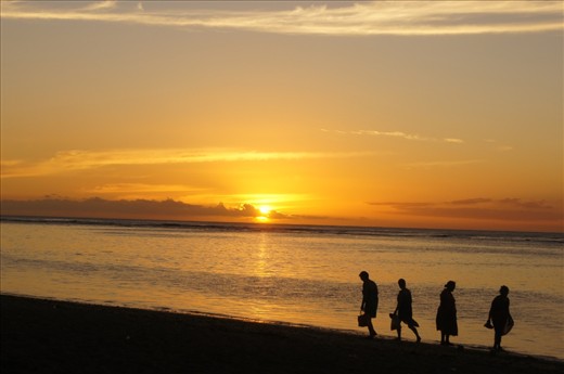 As the sun descends behind the clouds in the horizon, the natives' mission is accomplished- to watch the setting sun. This shows just how simple their lives are, and the immense beauty of its simplicity. 