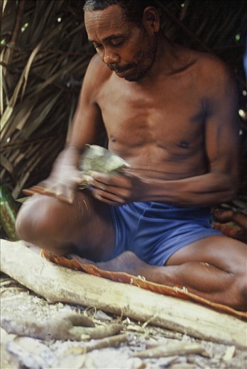 An elder from the nomadic tribes of Malaysia making blow darts for hunting