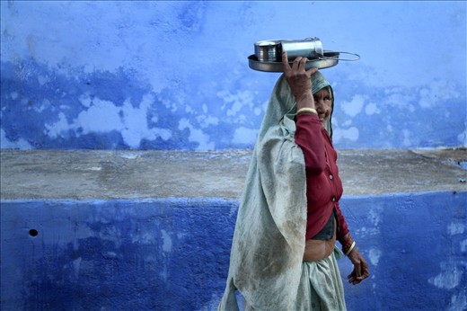 An Indian woman, carries utensils on her head at a  remote village 