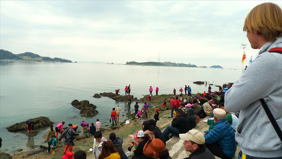 Onlookers gaze at the calm sea.