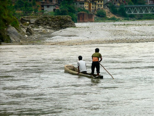 Two young boys travel down the river in their hand carved boat.