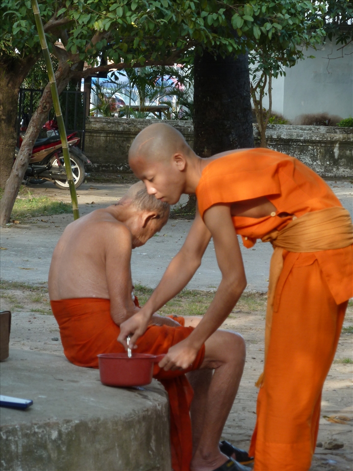 A young monk prepares an ederly monk for head shaving