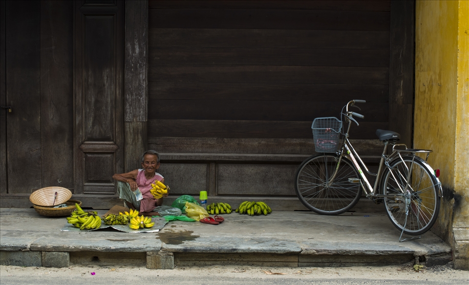 A happy old man in his banana shop