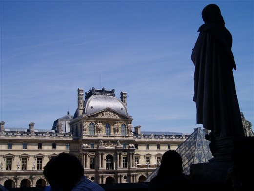 A watcher atop the Louvre Paris surveying a clear skyline.