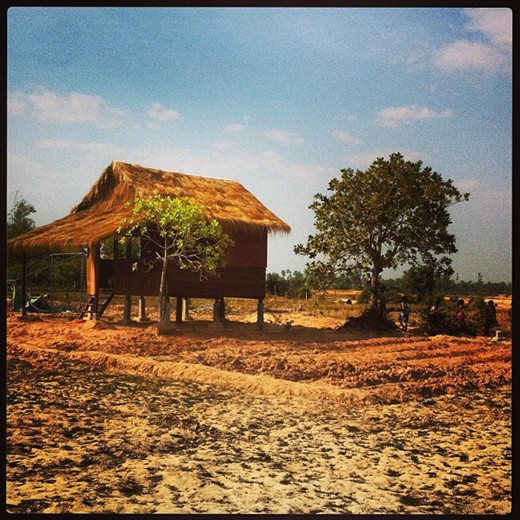 A village hut in Cambodia, kids playing by the tree
