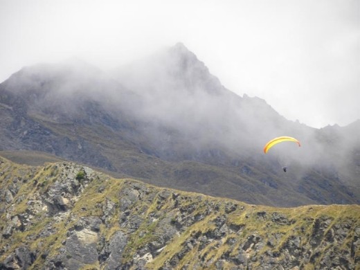 A parachutist gliding through the valley on the thermals.