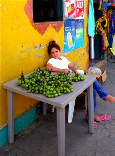 Life’s tough, long days, a young girl sells fruit on a sidewalk in Mayogalpa