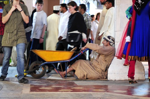 In noon, inside Muttrah suq, a man is waiting for bread among crowd.