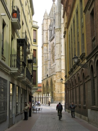 At the end of a narrow street, the Basilica of San Isidoro peeks out from behind city buildings in the center of quaint Leon, Spain.  