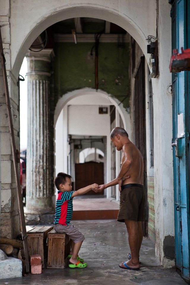 Mr. Soon taking a break on a Sunday, playing with his grandson at the five feet way in front his home.