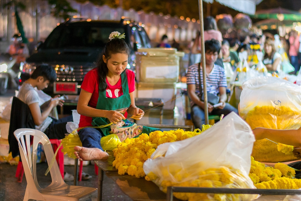 Bangkok, flowers market. a woman doing a flower chain.