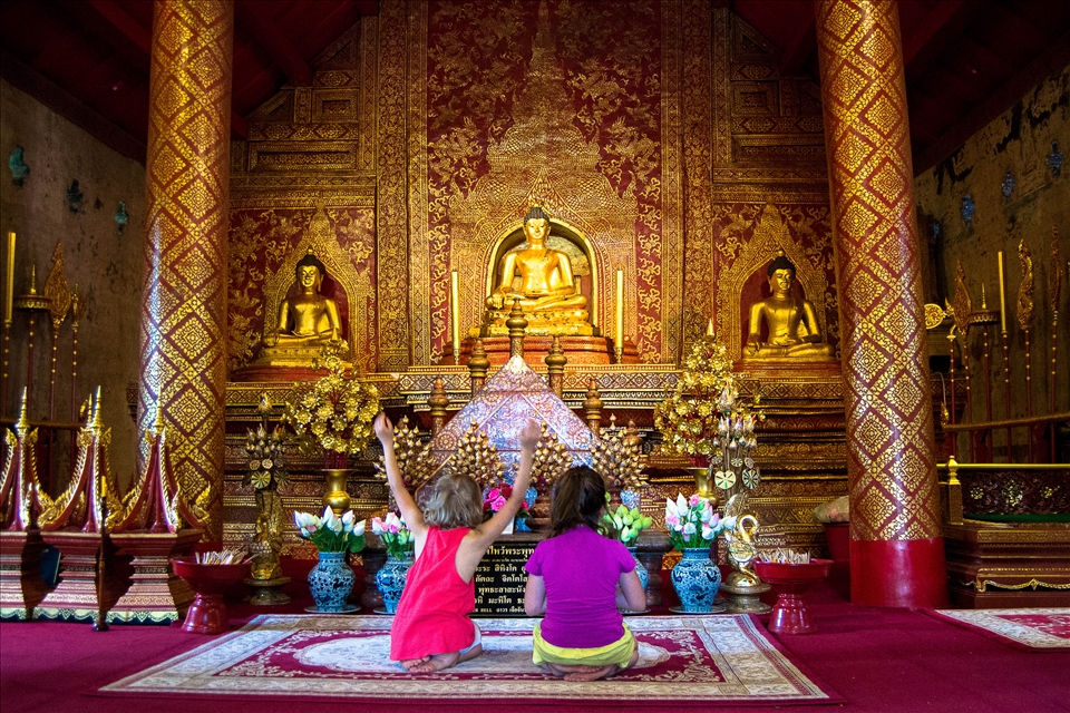 Chiang mai, little french girls imitate thai people praying in a buddhist temple