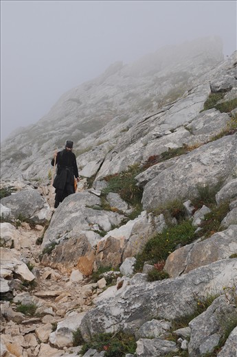 Walking down from the top of the mountain alone, between the mist and the wild rocks.