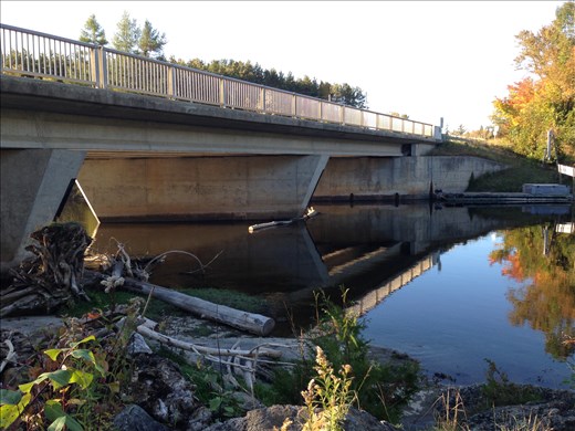 Bridge over still water, leading to waterfall. The calm before the storm. 