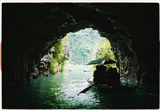 A ferry is going through a cave in Trang An. Crossing the caves, we have seen a forest of stalactites and stalagmites formed by water drops for many years.  