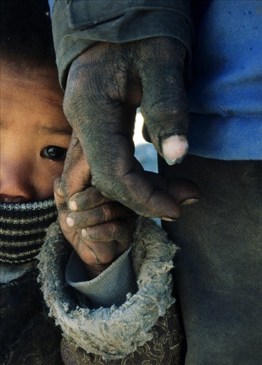 Traveling from Zhangmu (Nepal-Tibet border) to the Tibetan capital - Lhasa you can see road workers all along the Friendship Highway. The Chinese industrialization has affected Tibet a great deal. But despite the Chinese government attempts to settle Chinese population across the Tibetan Plateau, the Roof of the World still remains a place where only the Tibetans can survive its harsh climate conditions. A Tibetan boy holding the hand of his father who works on the road construction, Tibet.