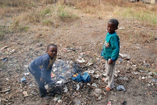 Two boys burning trash in the street.