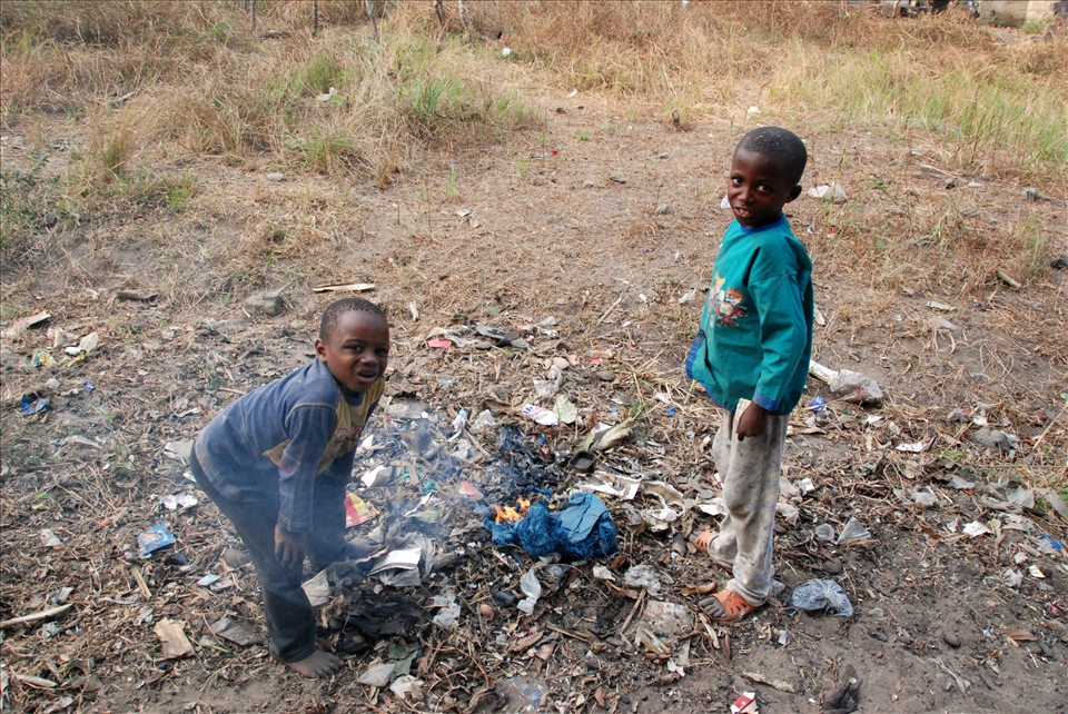 Two boys burning trash in the street.