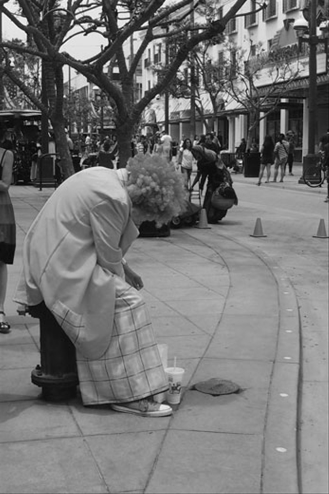 Los Angeles. Clown and out. A street performer casts a dark shadow. 