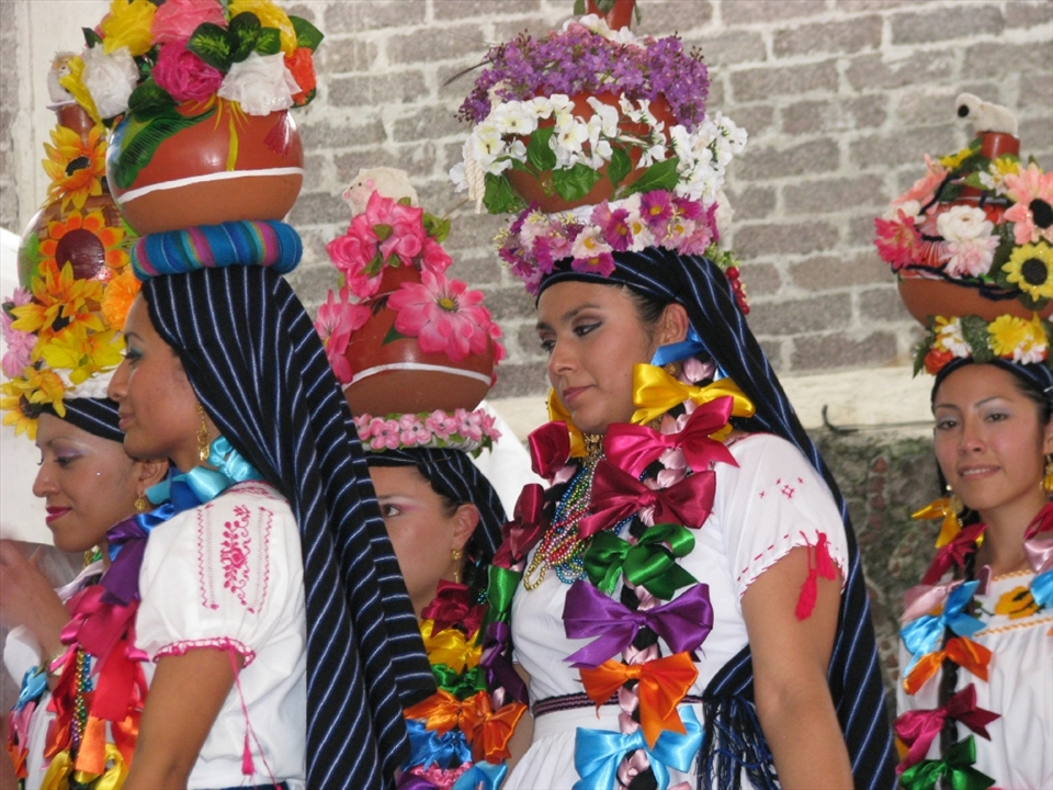 Women dancing and wearing typical dresses  from Mexico during a festivity.