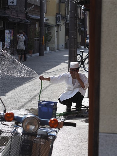 Kyoto, Japan: In the Gion district, a chef washes the pavement in front of his restaurant in preparation for the evening crowds. This age-old tradition continues throughout Japan today, symbolizing that a shop is clean and making it more inviting to passersby. The lazy tranquility that currently enrobes Gion belies the frenetic energy that will soon course down its cobbled lanes, as the neighborhood is one of the few remaining areas where geisha continue to live and work.