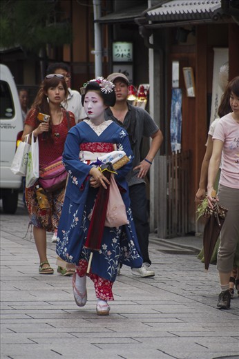 As the sun begins its descent, the streets of Gion burst to life in a frenzy of activity as geisha emerge from their living quarters — like rabbits from their dens — to attend the first of the evening’s appointments. Visitors travel from far and wide to Gion hoping to catch a glimpse of these rare and romanticized figureheads of Japanese culture. This apprentice geisha, or maiko as they are locally known, glances about anxiously, anticipating the overly eager entourage of strangers that will soon swarm her.