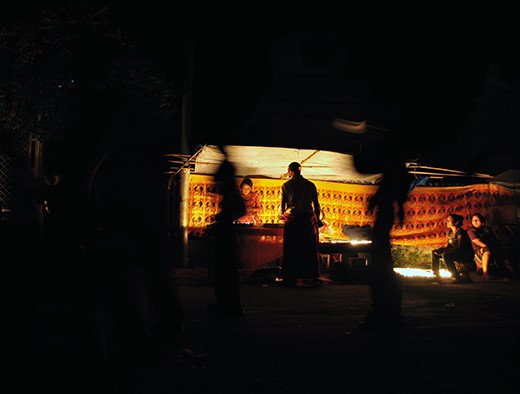 Buddhist Monk takes a detour and lights a candle in worship and goodwill. 