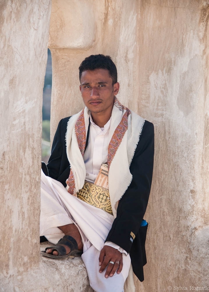 A Yemeni sitting on top of Dar al Hajar, the Imam’s Rock Palace, outside of Sana’a. He is wearing the Jambiya, a traditional dagger worn by men as an accessory. The material and design of the handle tells the status of the one wearing it.