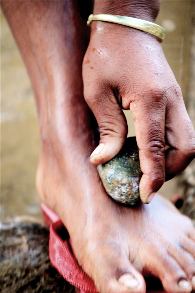 Young women of the village use stones to remove body hair while bathing