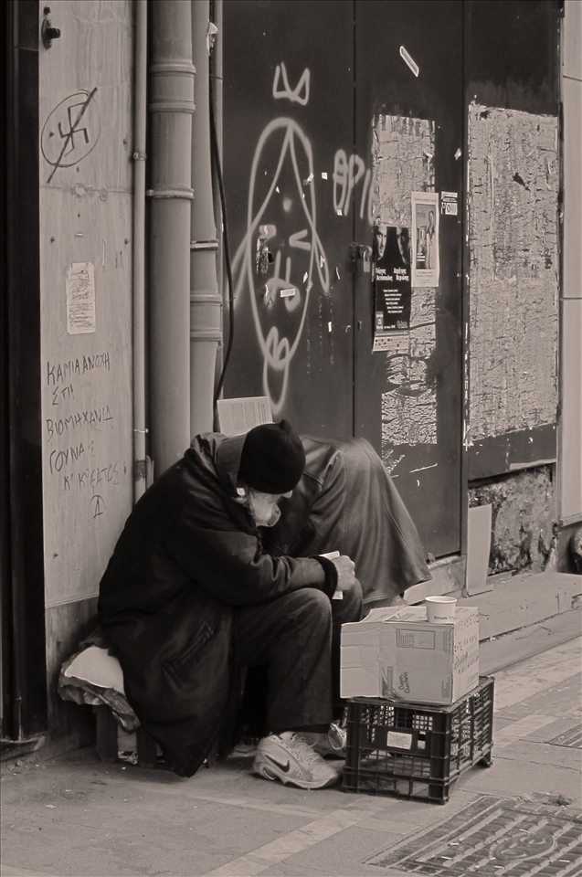 There is still hope in this place. A homeless man doesnt beg only for money but he reads a book something that someone may not expect in such a case. Antifascist symbol written on the wall is another push for our society. 