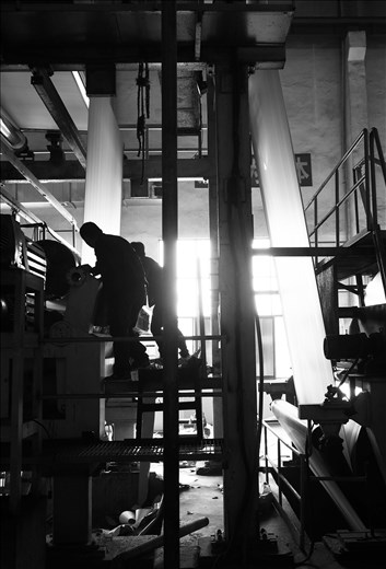 Workers undertake maintenance on an older paper machine at a mill in Fuyang, China