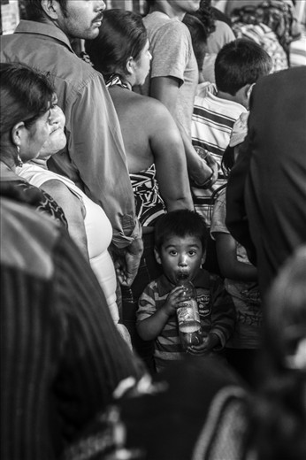 A young boy is playing with a plastic bottle after having been standing in line for over two hours with his family. On October 28 people come from all over the country to visit the Maximon altar in San Andrés Itzapa. Most are Christian. 