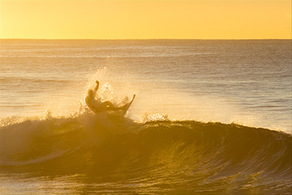 Tim carving it up on the waves as the sun rises behind him