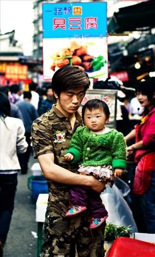 In a country that is developing very fast, family traditions are still strong. Here is a father with his child at Shanghai's Old City Market, both characters look thoughtful and in some way worried.