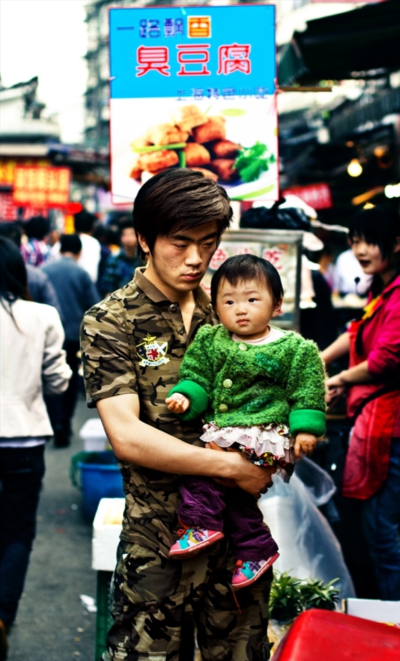 In a country that is developing very fast, family traditions are still strong. Here is a father with his child at Shanghai's Old City Market, both characters look thoughtful and in some way worried.