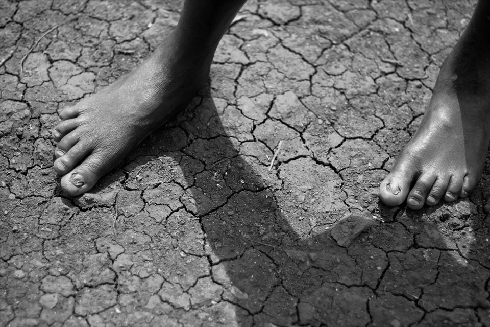 After this child has walked all morning to gather fresh water his feet almost blend into the backdrop of the cracked earth.