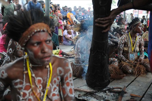 A man heats a drum among women in the Asmat Culture Festival. In their ritual beliefs, fire is something sacred. Their ritual activities always start by making a bonfire. Catholicism slowly replacing religious beliefs because it provides protection for the vulnerable acts of violence, especially for women and children. Asmat women are easier to believe in the Catholic teachings than their men.