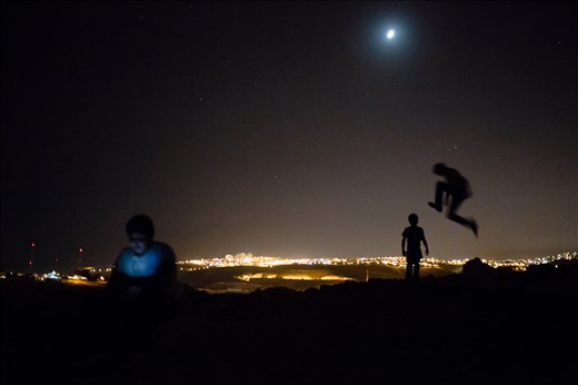 Sulieman and Tiger plays on the hill behind their Bedouin village while Ali plays a game on his cell phone. In the background is one of Israel’s largest settlements, Ma’ale Adumim. The boys have never been in the settlement – it is forbidden to the inhabitants of the Bedouin communities.