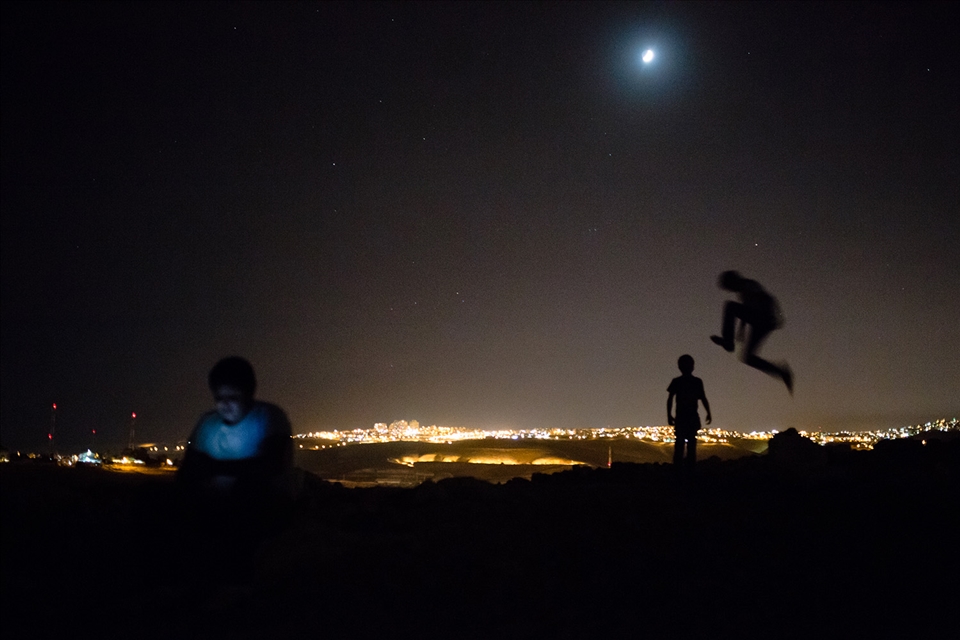 Sulieman and Tiger plays on the hill behind their Bedouin village while Ali plays a game on his cell phone. In the background is one of Israel’s largest settlements, Ma’ale Adumim. The boys have never been in the settlement – it is forbidden to the inhabitants of the Bedouin communities.