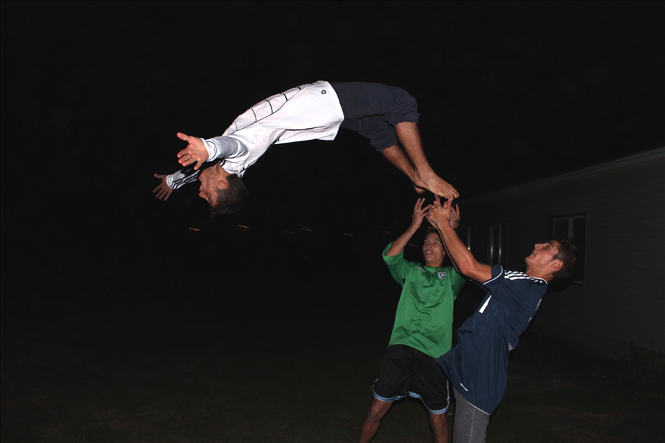 Aiming High: young men show off their acrobatic skills for a young female visitor to their countryside home.